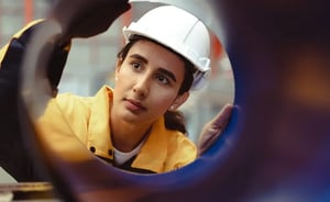 Mujer con gafas de seguridad y chaleco reflectante utilizando una tableta en una planta industrial de fabricación de productos de madera.