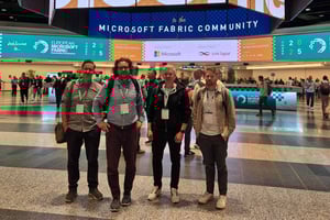 Fyra dataspecialister från Pinja poserar på Microsoft Fabric Community-konferensen, med den stora eventhallen och officiella banderoller i bakgrunden.